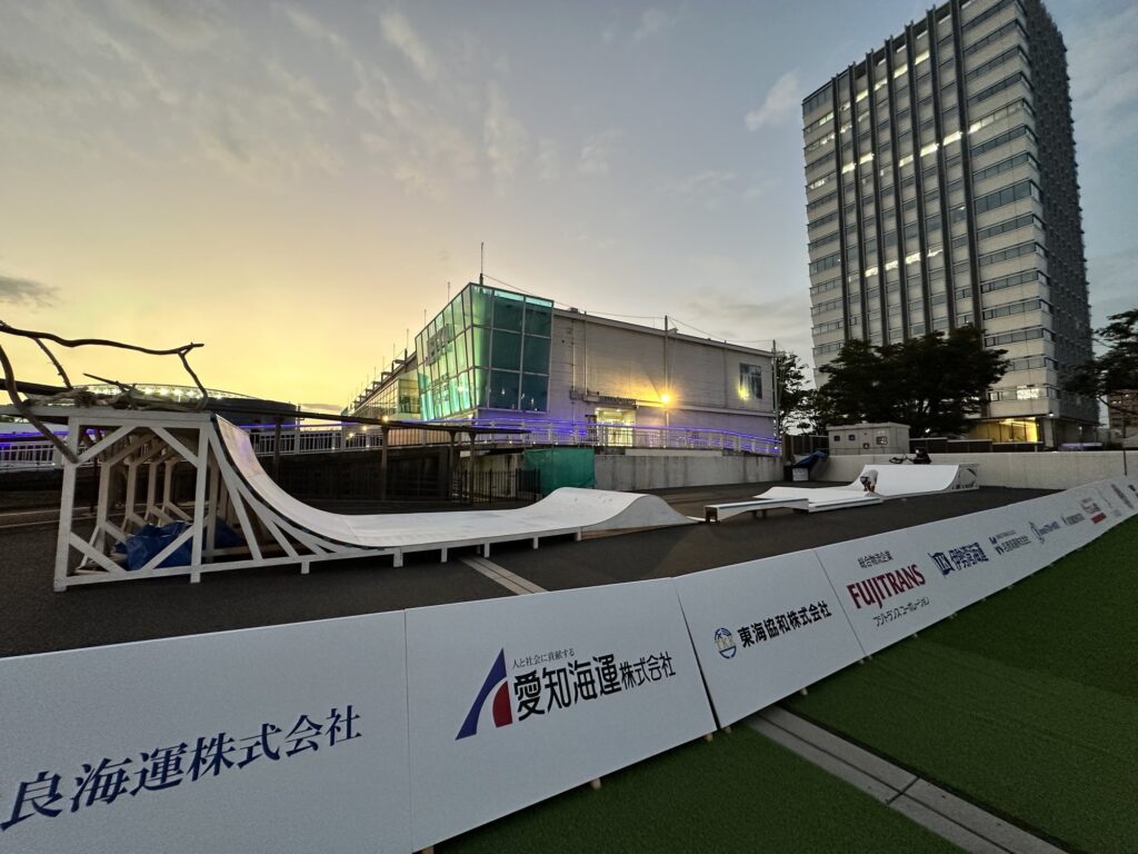 アーバンスポーツパーク全景（夕景）。手前からH1800クォーターパイプ、ビッグウェーブ、奥にグラインドボックスとH1000クォーターパイプ。右手前はスポンサーボード